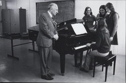 [Music Education at NCPE, depicting a piano teacher with a female student playing the piano and three fellow students observing.]