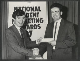 Seamus Brennan presenting a national student marketing award to an unidentified recipient