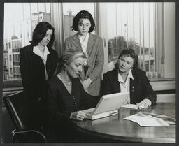 Four women gathered around a laptop or word processor