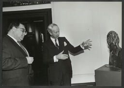 Dr Ed Walsh with an unidentified male looking at a sculpture