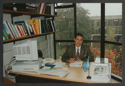 Graduation shots, individual sitting at office desk