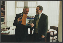 Professor Noel Whelan and another individual looking at a book titled "American Institute for Foreign Study 1999-2000"