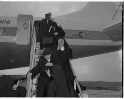 Nuns and Vicar General Salesians arriving down steps of Pan American Airlines (PAA) Jet